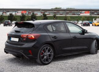 Czarny hatchback Citroëna zaparkowany na dużym, otwartym parkingu