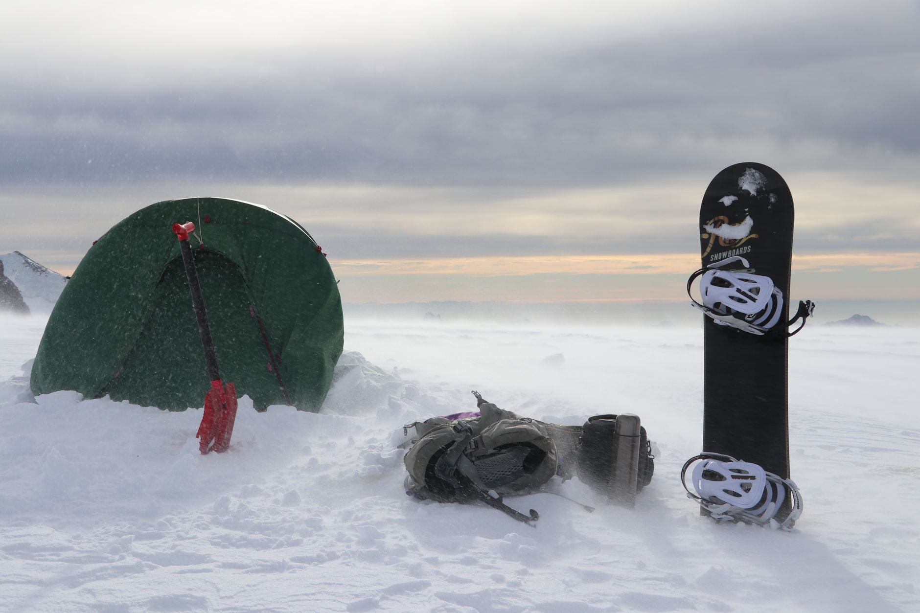 Zimowy biwak w górach z namiotem, snowboardem i plecakiem na śniegu