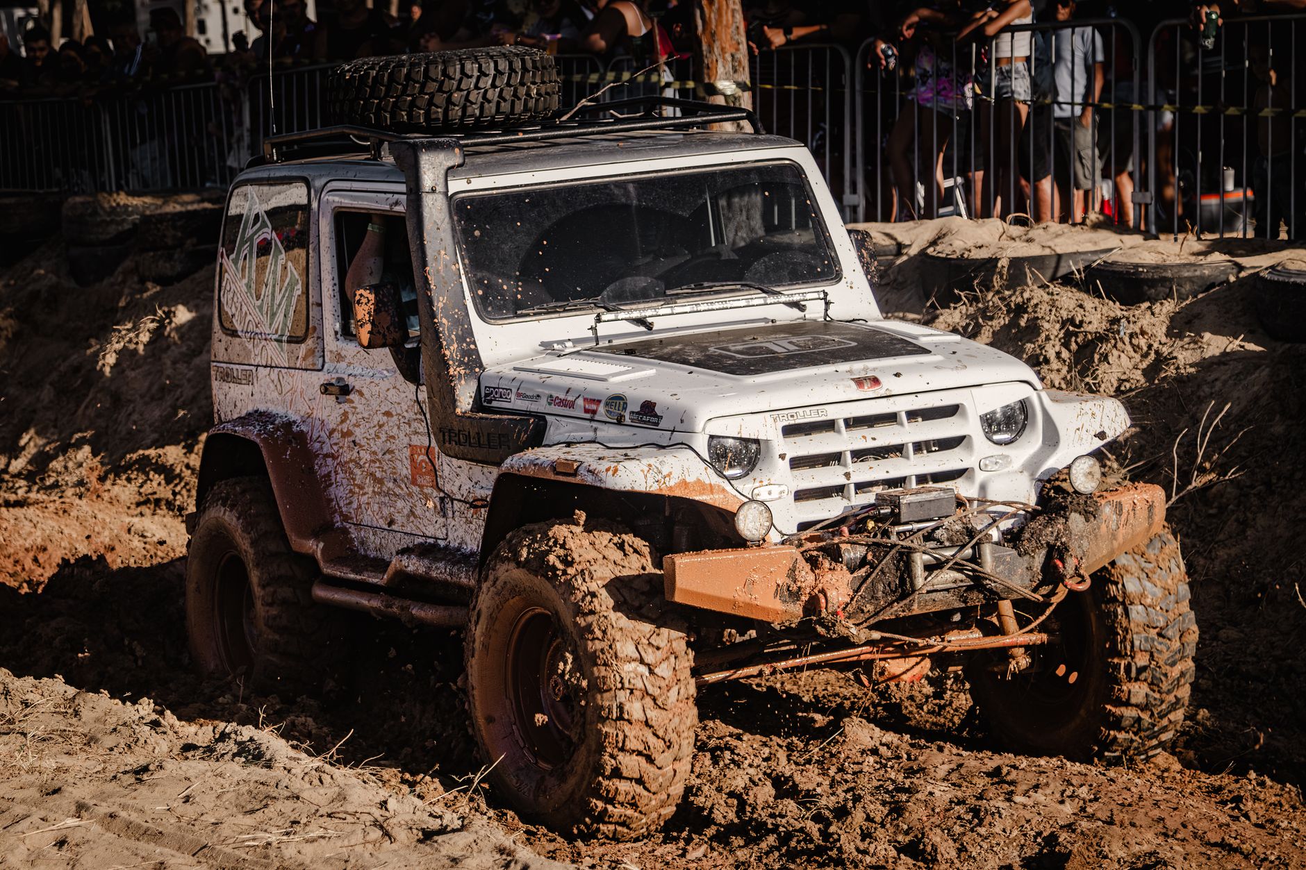 Biały Jeep 4x4 jedzie po błotnistej trasie rajdowej