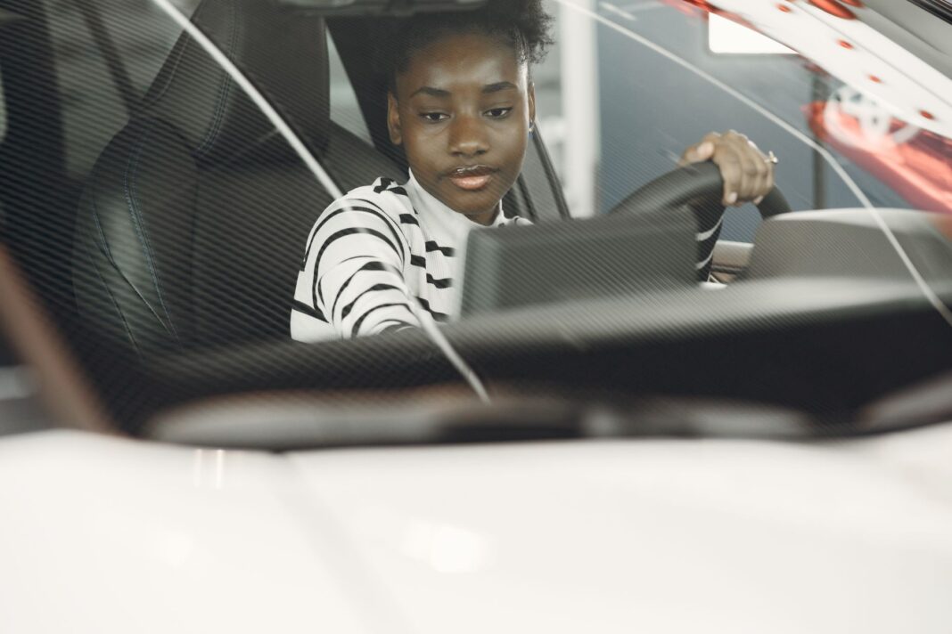 Młoda kierowczyni prowadzi samochód, widok z wnętrza na kierownicę Młoda kierowczyni prowadzi samochód, widok z wnętrza na kierownicę