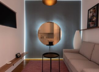 Nowoczesny salon z sofą, telewizorem i okrągłym lustrem na ścianie