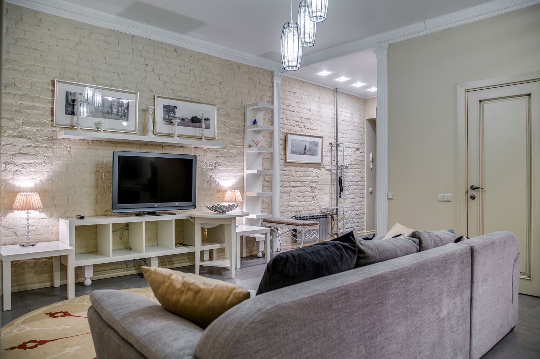Przytulny nowoczesny salon z telewizorem, ceglaną ścianą i dekoracjami