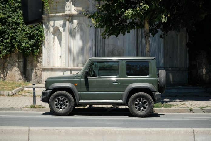 Zielone Suzuki 4x4 zaparkowane na słonecznej miejskiej ulicy Zielone Suzuki 4x4 zaparkowane na słonecznej miejskiej ulicy